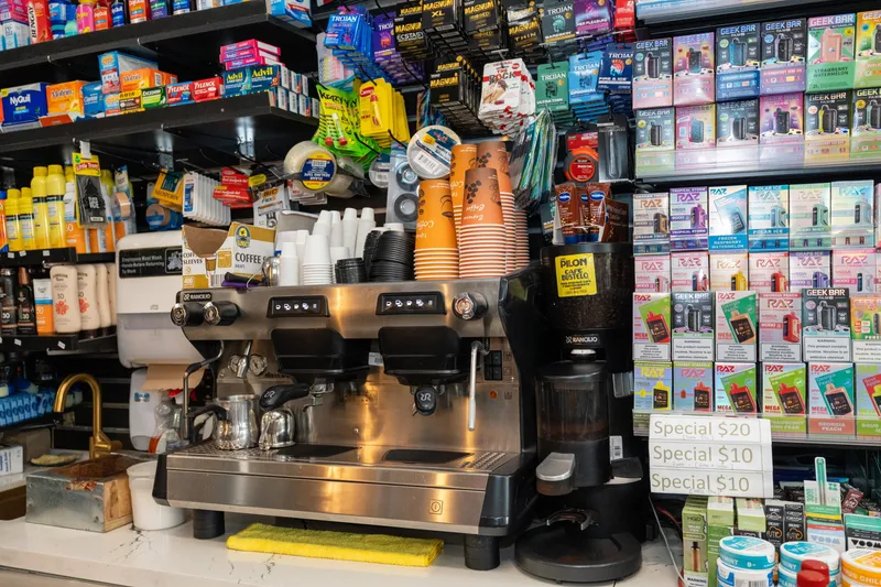 The espresso machine and coffee grinder behind the WYN MKT counter, with stacks of to-go cups