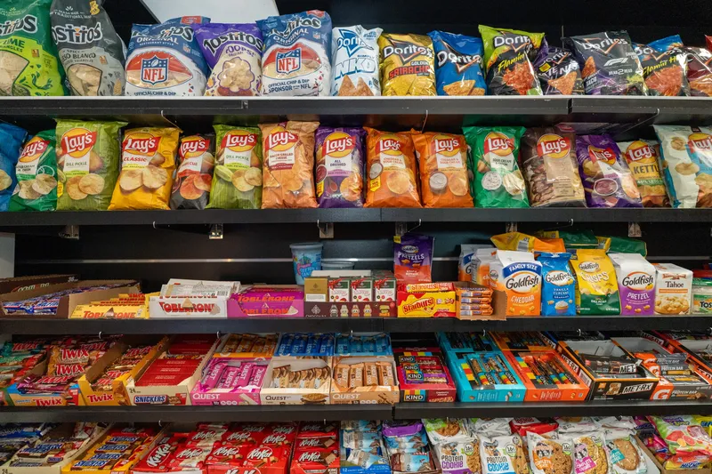 WYN MKT snack shelves stocked with Lay's, Doritos, Tostitos, Goldfish, Toblerone, Twix, KitKat and Kind bars